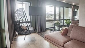 A modern living room with a hanging chair, a sofa, a flat-screen TV, and large windows offering a city view.