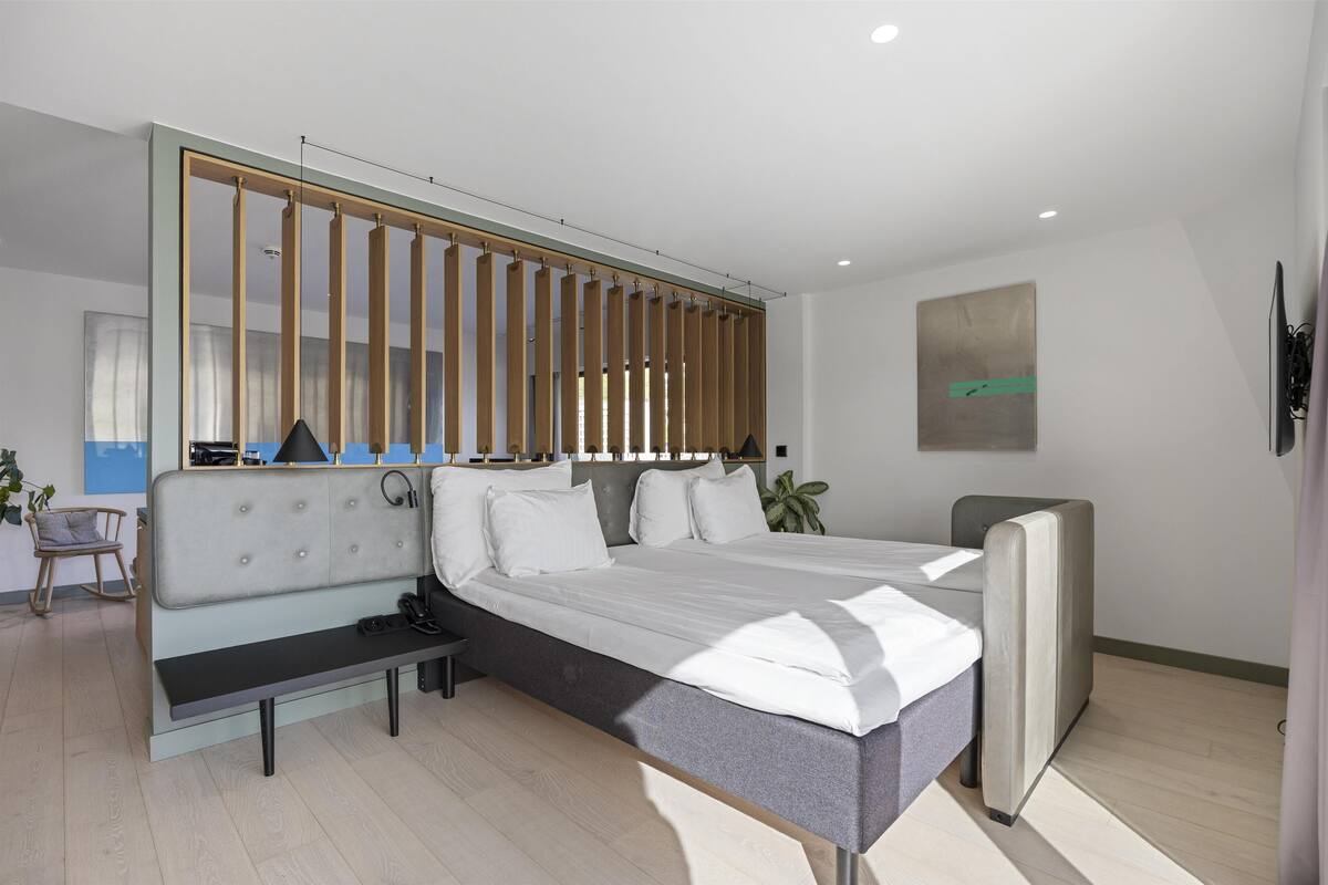 A modern bedroom with a bed, bench, and a large window.