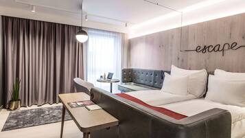 Una habitación de hotel moderna con un sofá cama, una mesita, una planta en maceta y una pared con la palabra "escape" escrita.