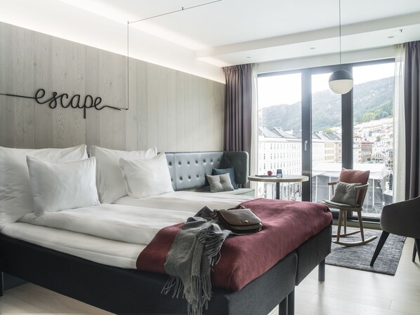 Habitación de hotel moderna con una cama grande, vista a la ciudad y la palabra 'escape' en la pared.