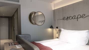 Una habitación de hotel moderna con una cama, un escritorio con una computadora portátil, un espejo y una pared con la palabra