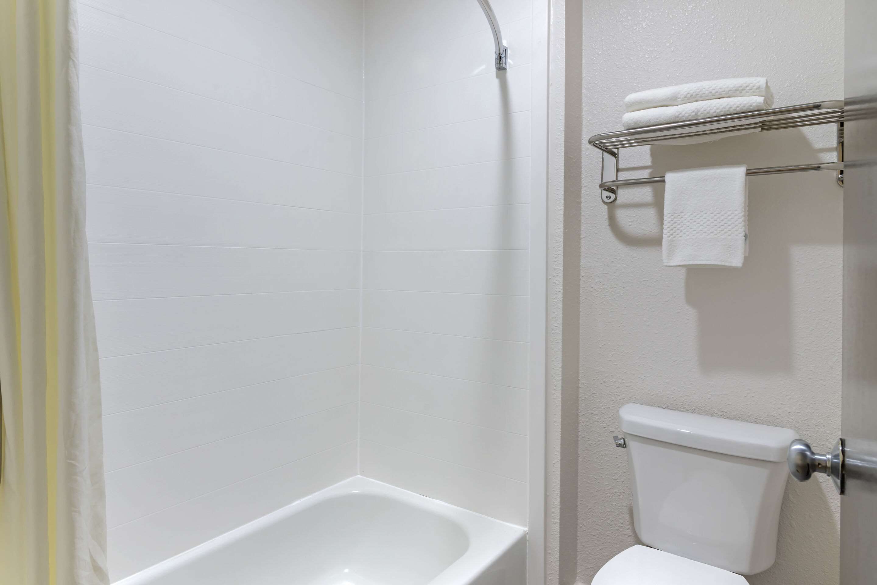 A bathroom with a bathtub, toilet, and a towel rack with towels.