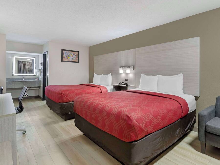 Habitación de hotel con dos camas, un escritorio y una silla.