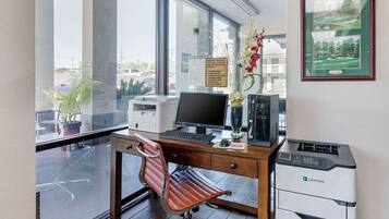 Un bureau moderne équipé d’un bureau, d’un ordinateur, d’une imprimante et offrant une vue sur l’extérieur.