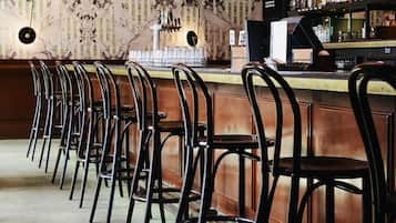Un bar avec un long comptoir, de nombreuses chaises et une variété de bouteilles exposées sur des étagères.