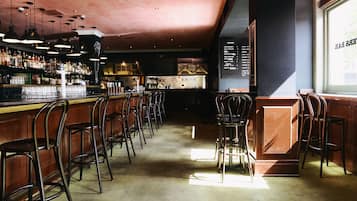 A bar area with multiple stools, a counter with bottles, and a menu board.