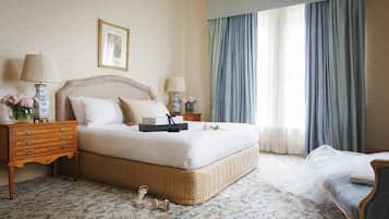 A neatly arranged bedroom with a large bed, a bedside table with lamps, and a chair.