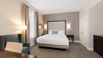 Een hotelkamer met een groot bed, een bureau, een stoel, een nachtkastje en een lamp.