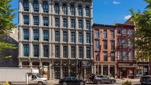 A historic building with large windows and a classic architectural style, featuring a sign for a restaurant and a barber shop.