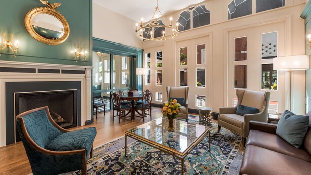 A spacious living room with a fireplace, a chandelier, and a large window with a view.