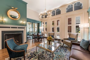A spacious living room with a fireplace, a chandelier, and a large window with a view.