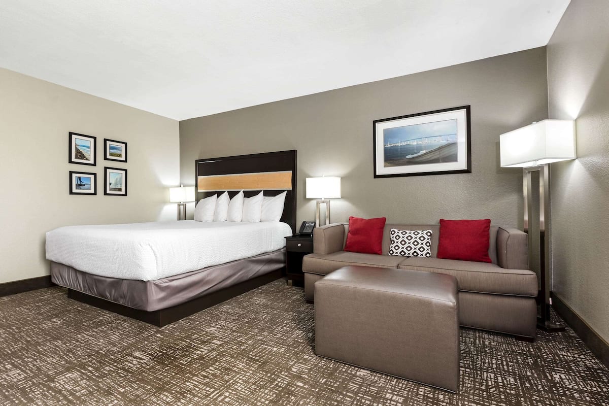 Een hotelkamer met een bed, een bank, een kleine tafel en een lamp.
