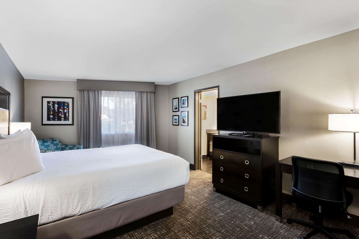 Een hotelkamer met een groot bed, een flatscreen televisie, een bureau met stoel en een dressoir.