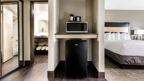 Habitación de hotel con cama, microondas y refrigerador.
