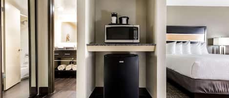 Habitación de hotel con cama, microondas y refrigerador.