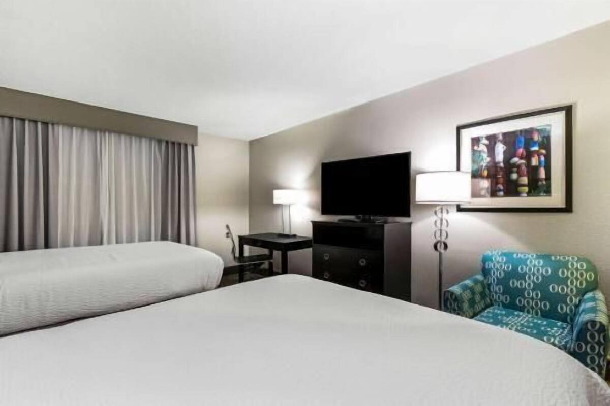Een hotelkamer met twee bedden, een flatscreen televisie, een bureau, een lamp en een stoel.