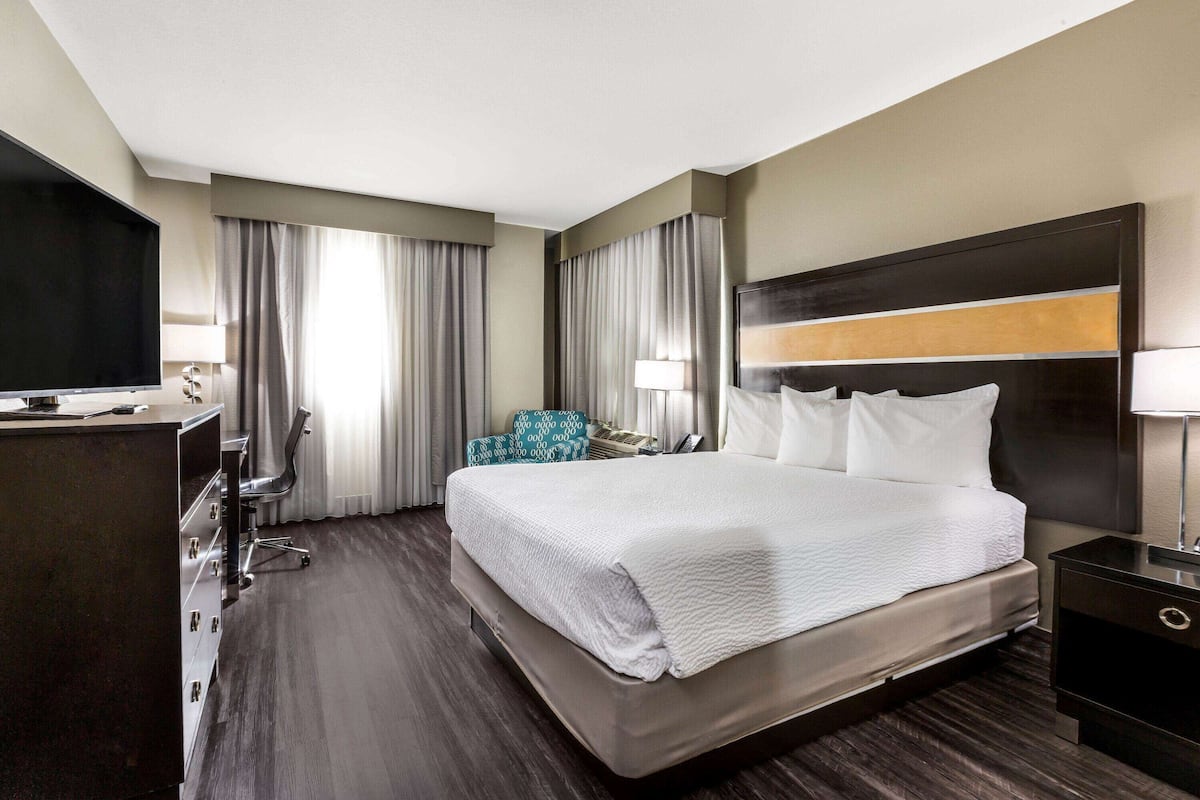 Een hotelkamer met een groot bed, een bureau met een flatscreen televisie, een stoel en een bureaulamp.
