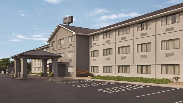 A modern hotel with a covered entrance, multiple floors, and a parking lot.