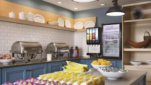 A breakfast bar with food items, a milk dispenser, and a refrigerator with beverage options.