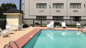 A pool area with clear water, a sign for Country Inn & Suites by Carlson, and a building with multiple windows and a flat roof.