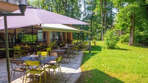 An outdoor dining area with tables and chairs, surrounded by trees. - ibis Nancy Brabois (Vandœuvre-lès-Nancy)