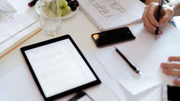 A workspace with a tablet, smartphone, and documents, including a floor plan.