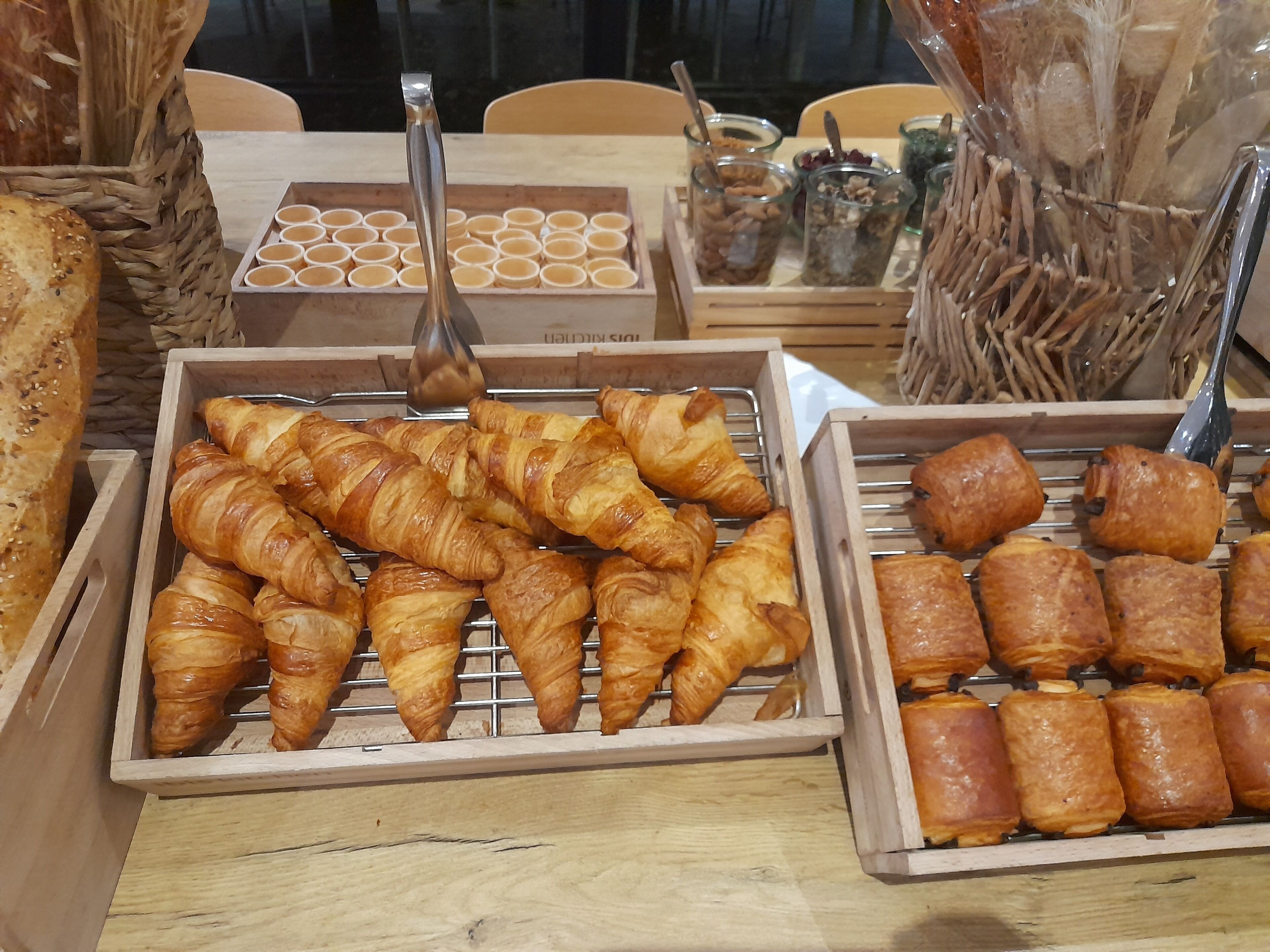 A display of various baked goods, including croissants and other pastries, arranged in wooden boxes.