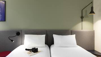 Habitación de hotel con dos camas, una lámpara de pared y un cuadro enmarcado.