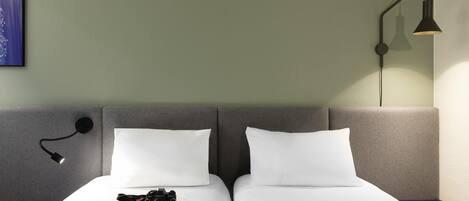Habitación de hotel con dos camas, una lámpara de pared y un cuadro enmarcado.