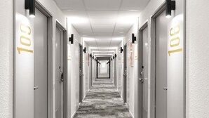 A hotel hallway with doors numbered 101, featuring a carpeted floor and wall-mounted light fixtures. - ibis Nancy Brabois (Vandœuvre-lès-Nancy)