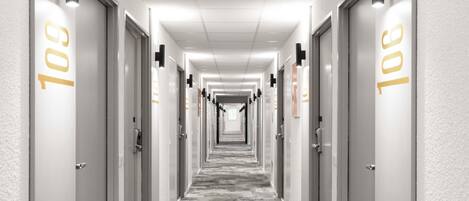A hotel hallway with doors numbered 101, featuring a carpeted floor and wall-mounted light fixtures.