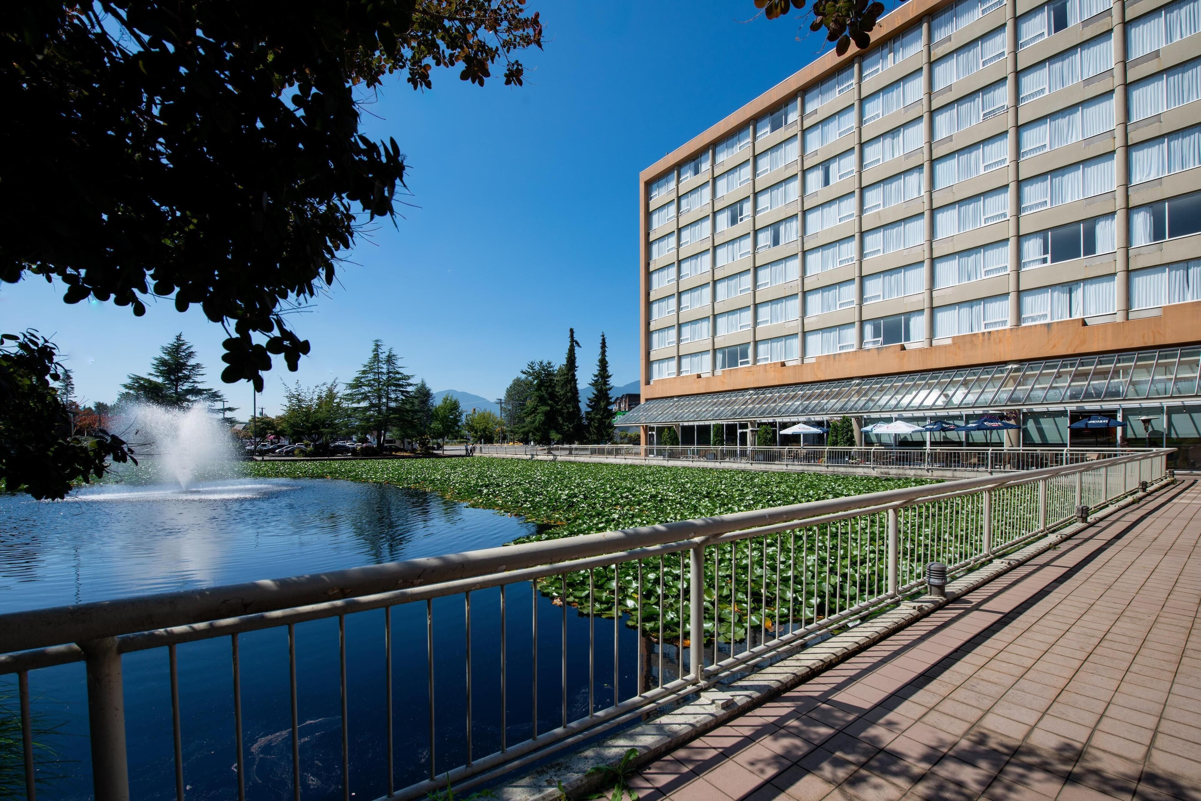 Ein Hotel mit einem großen Gebäude, einem Teich mit Seerosen und einer Springbrunnen.