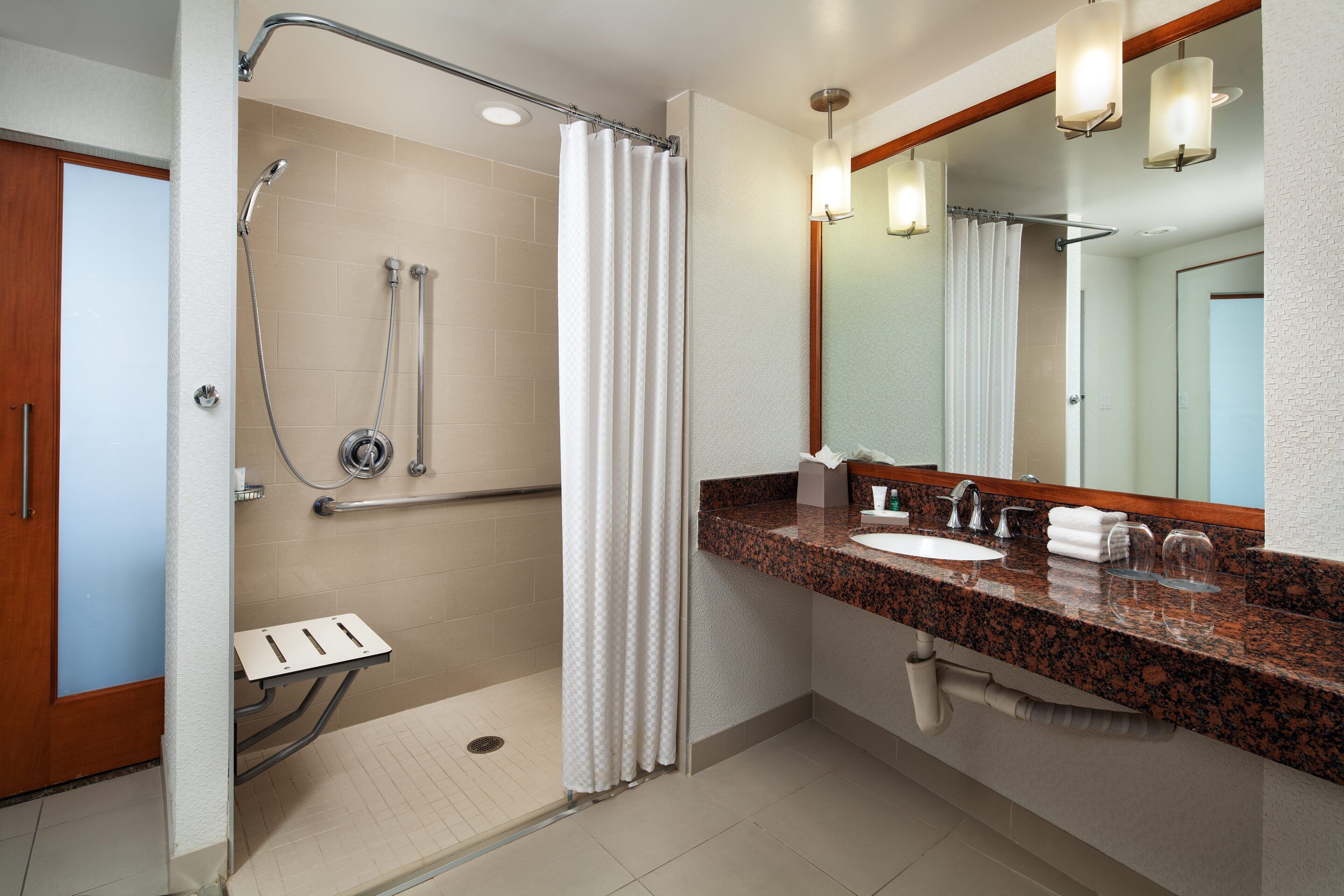 A modern bathroom with a shower, a sink, and a vanity mirror.