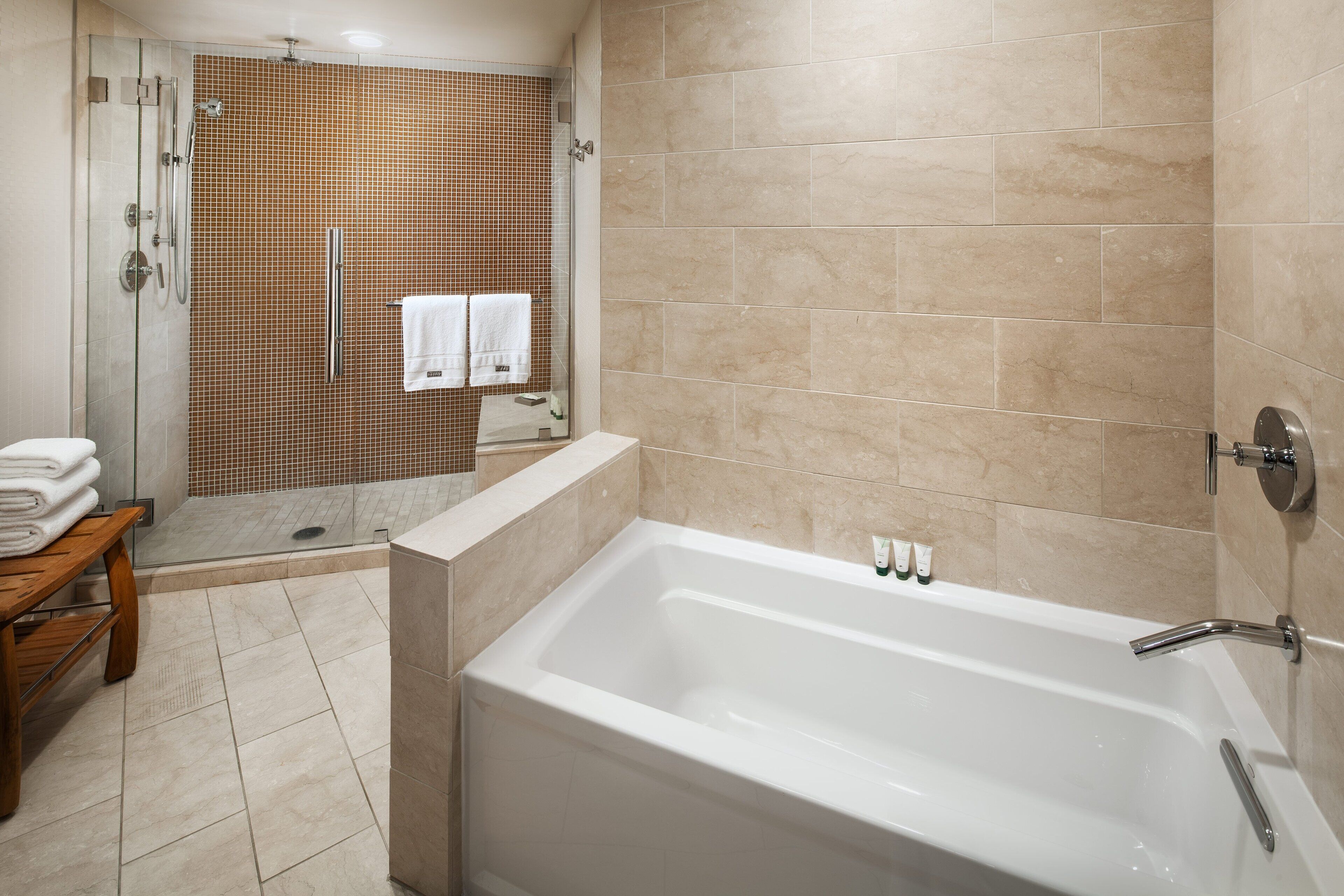 Une salle de bain moderne avec une douche à parois de verre, une baignoire blanche et un banc en bois.
