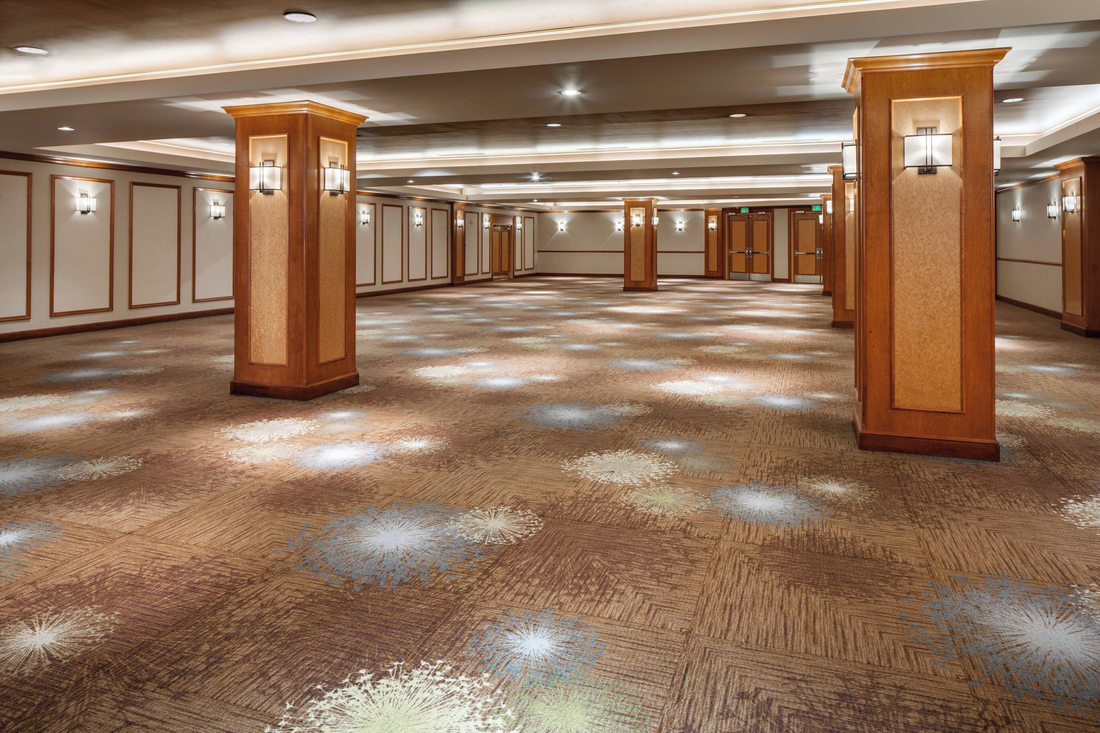 A spacious hotel lobby with high ceilings, wooden pillars, and recessed lighting.