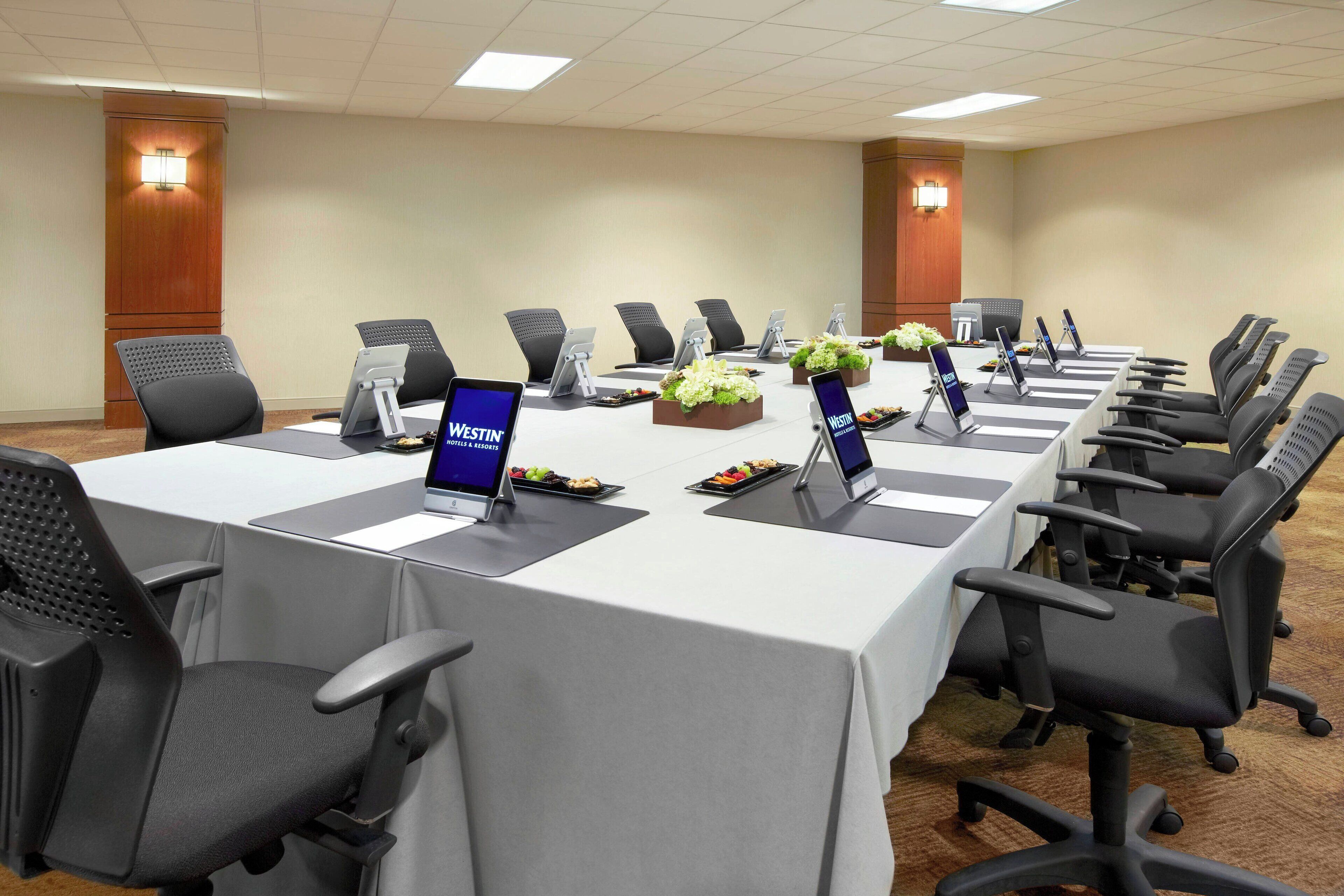 A conference room with a long table, multiple chairs, and laptops.