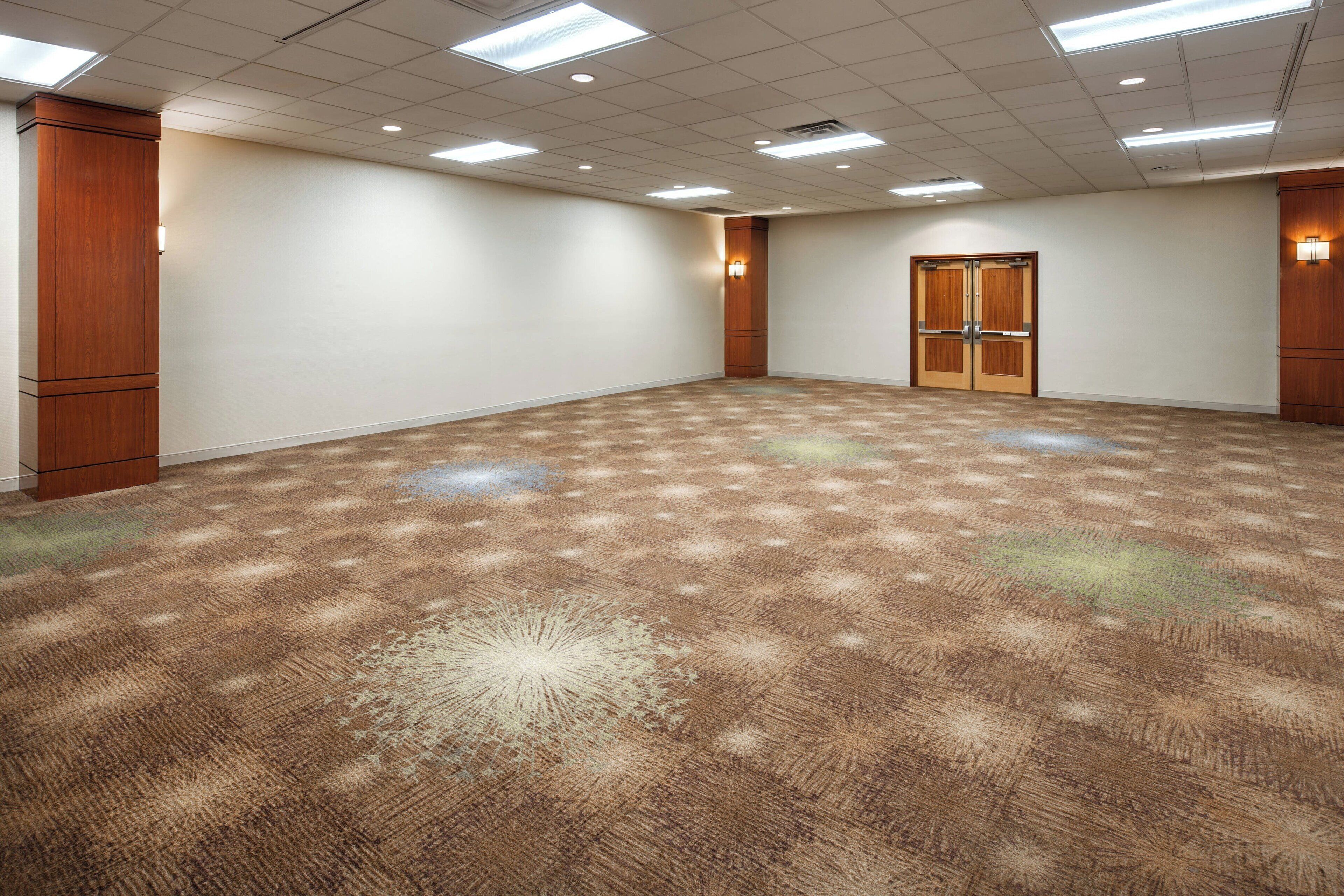 Une salle de conférence dotée d’un sol recouvert de moquette, de lambris en bois et d’une porte avec un luminaire.