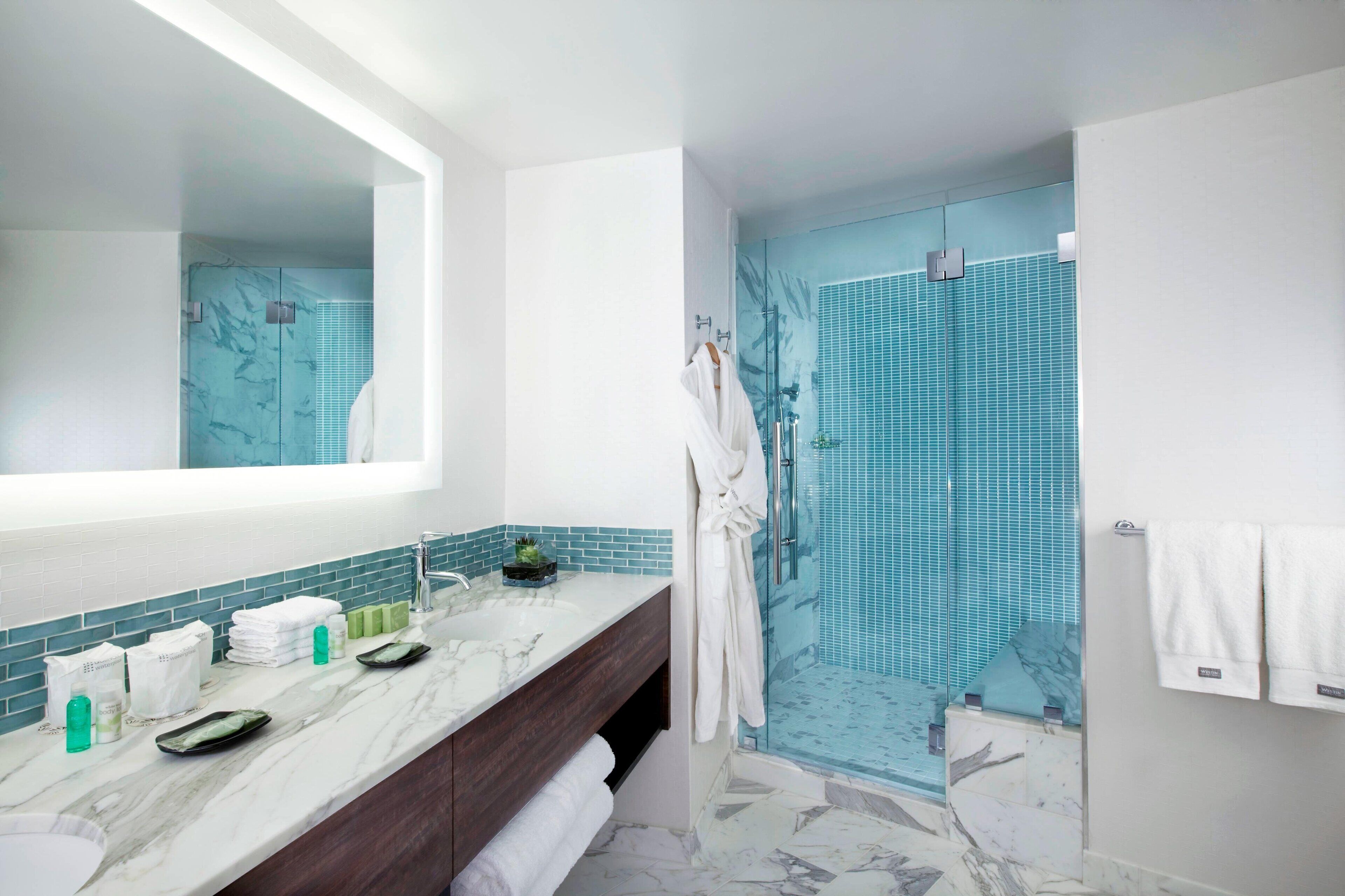 Un bagno moderno con un vanità in marmo, cabina doccia in vetro e uno specchio grande.
