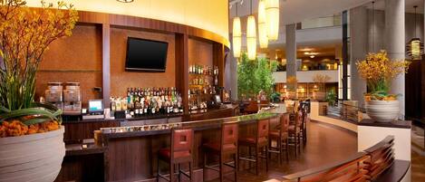 A modern bar area with a curved counter, multiple bar stools, and a large potted plant.