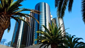 A modern high-rise building with a curved glass facade, surrounded by palm trees. - The Westin Bonaventure Hotel and Suites, Los Angeles (Los Angeles)