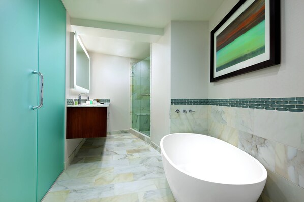 Een moderne badkamer met een vrijstaand bad, een douchecabine met glazen wanden en een betegelde vloer.