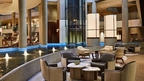 A spacious indoor lobby with a central water feature, seating areas, and a modern elevator. - The Westin Bonaventure Hotel and Suites, Los Angeles (Los Angeles)