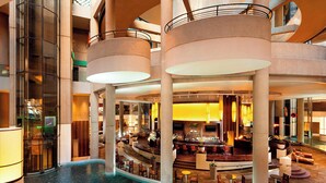 A spacious lobby with a central bar area, multiple seating arrangements, and a pool. - The Westin Bonaventure Hotel and Suites, Los Angeles (Los Angeles)