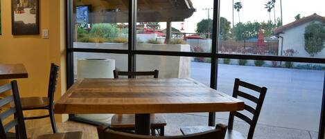 A restaurant interior with a large window, wooden tables, and chairs.