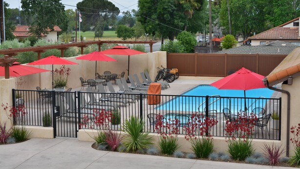 A backyard with a pool, patio furniture, and red umbrellas. - Casa Ojai Inn (Ojai)