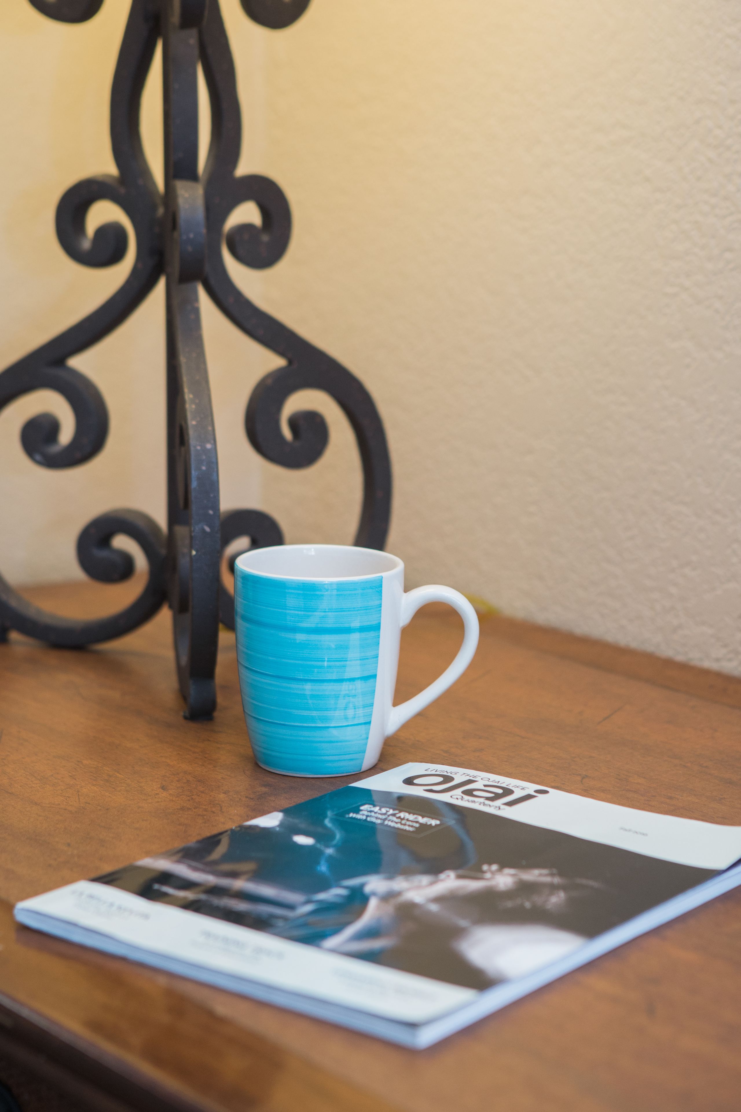 A blue mug on a wooden table with a magazine.
