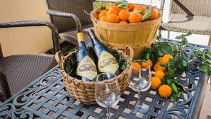 A metal table with wicker chairs, a basket of oranges, bottles of wine, and a glass of wine. - Casa Ojai Inn (Ojai)
