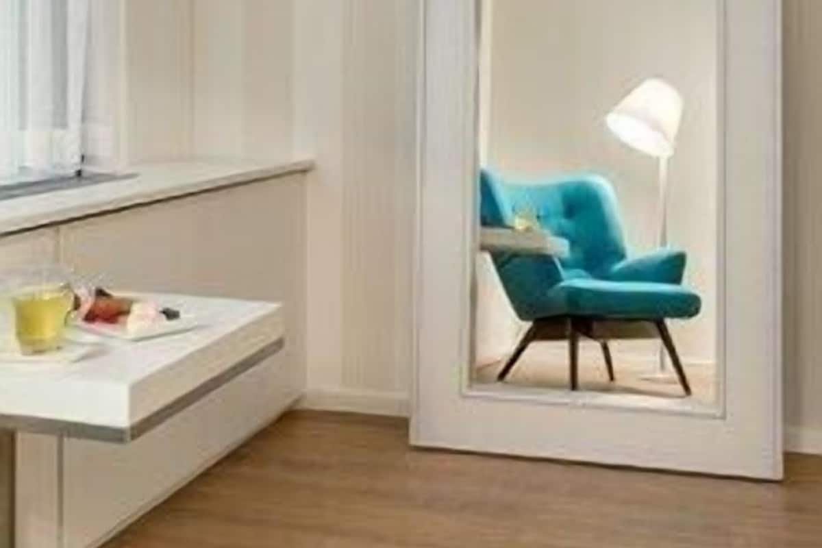 A room with a sliding door, a blue chair, a lamp, and a small table with items on it.