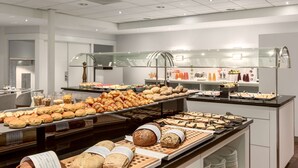 A buffet area with various baked goods and pastries displayed on trays.