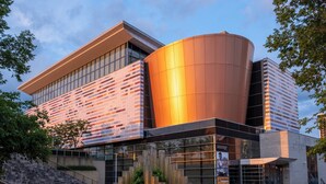 A modern building with a curved glass facade, a prominent cylindrical structure, and a staircase leading to an entrance. - Crowne Plaza Louisville Airport Expo Ctr by IHG (Louisville)